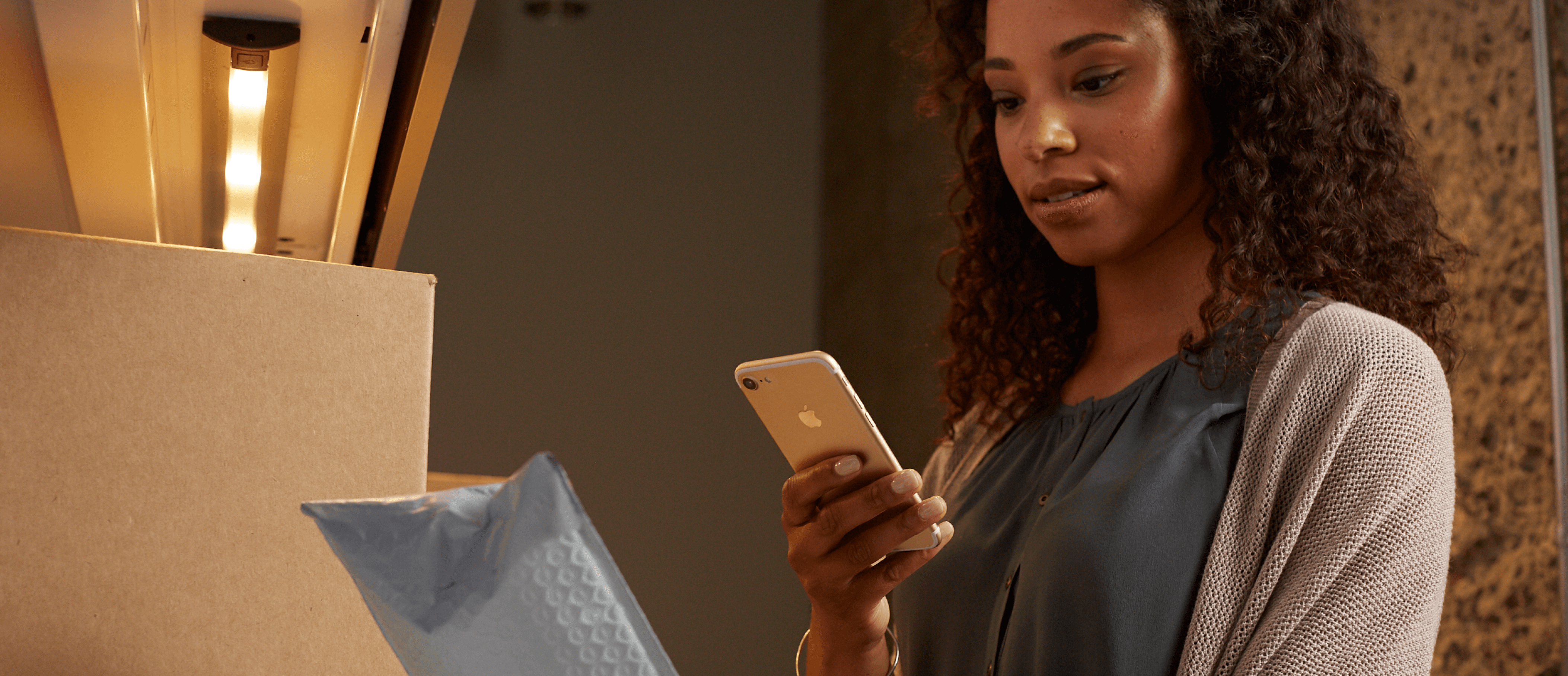 Photo of a woman looking at her phone, scanning a package that arrived