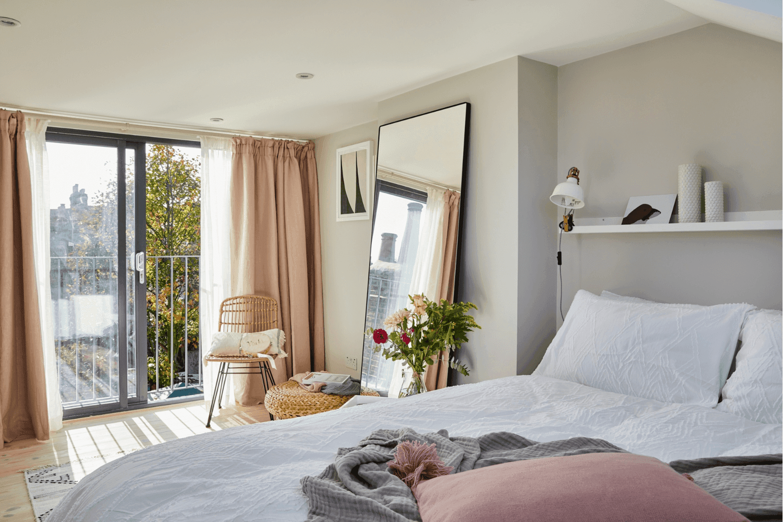 A South West London loft conversion showcasing a bedroom with a pink comforter and a window.	