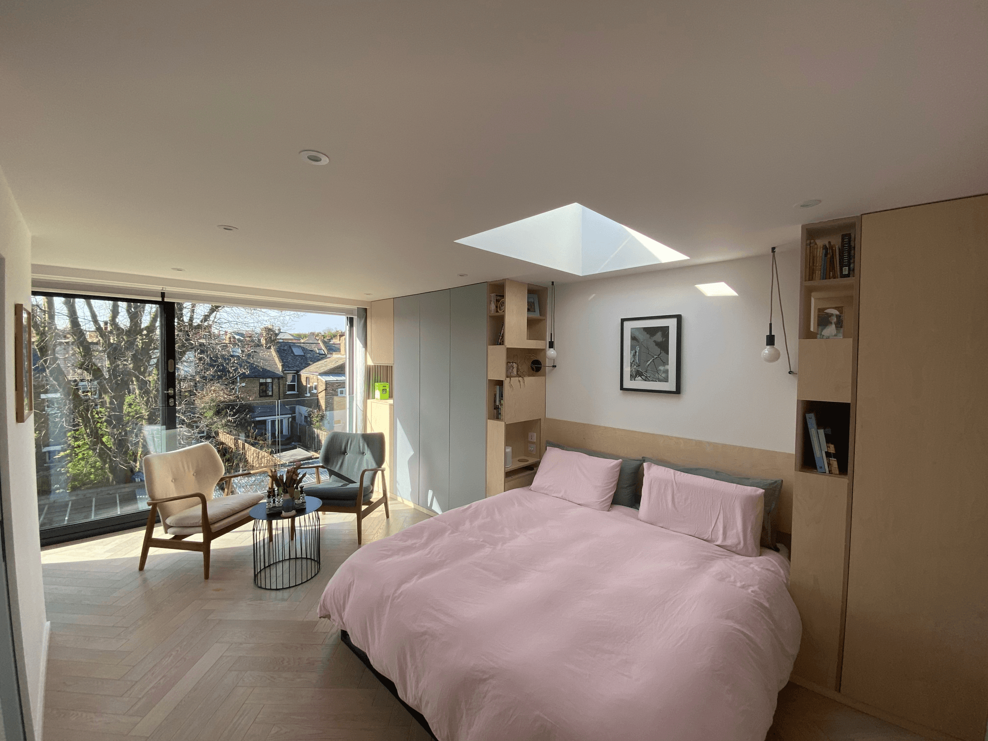 A South West London loft conversion showcasing a bedroom with a pink comforter and a window.	