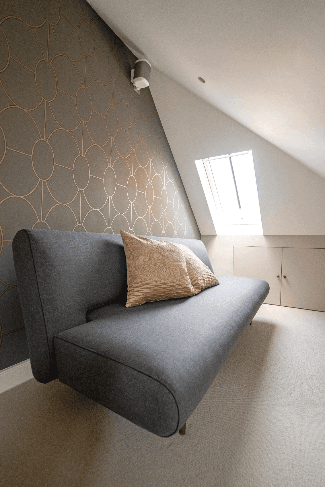 A grey couch in a skylight-lit room.	