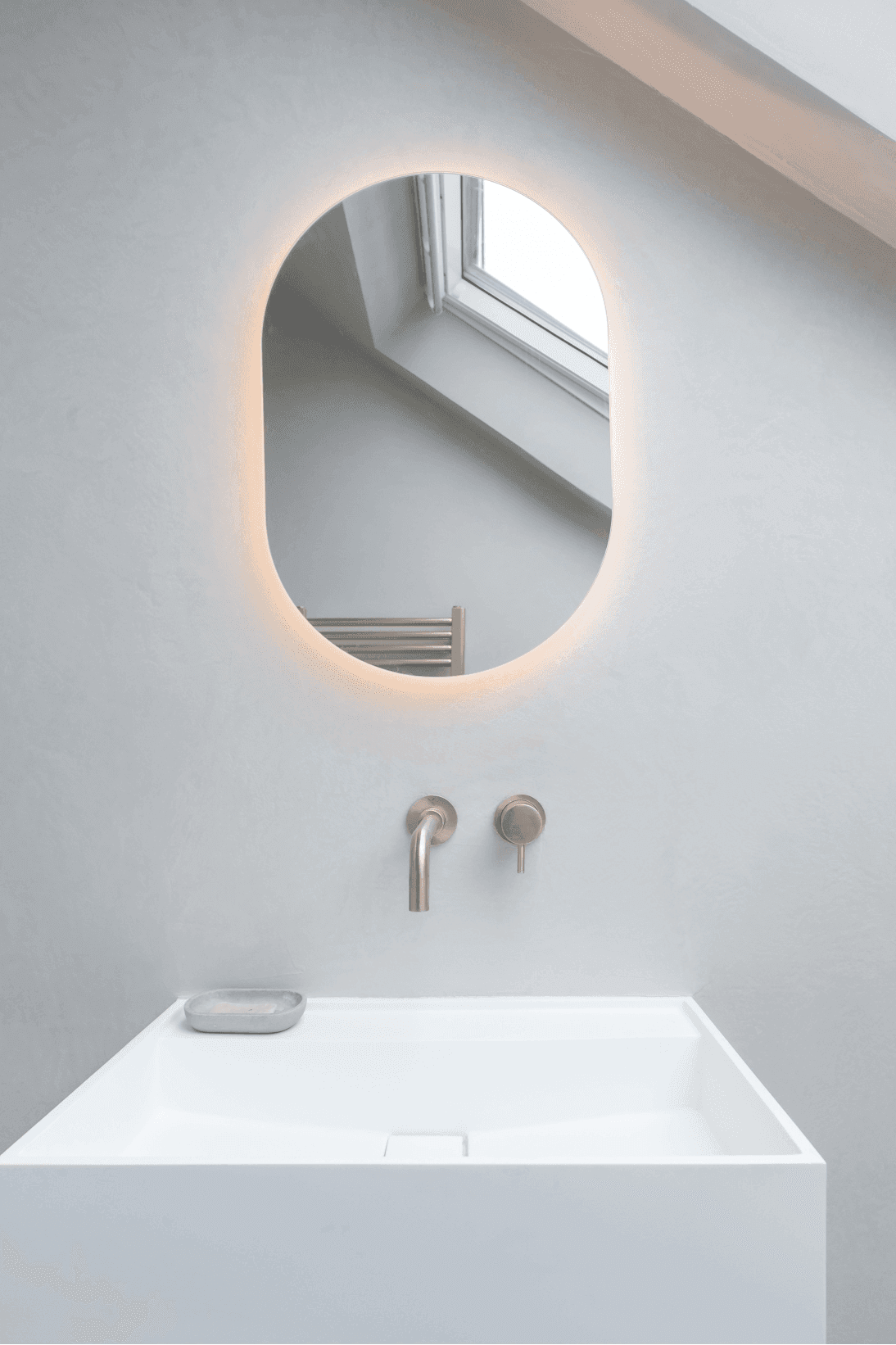 A white bathroom with a circular mirror above a sink in South West London.	