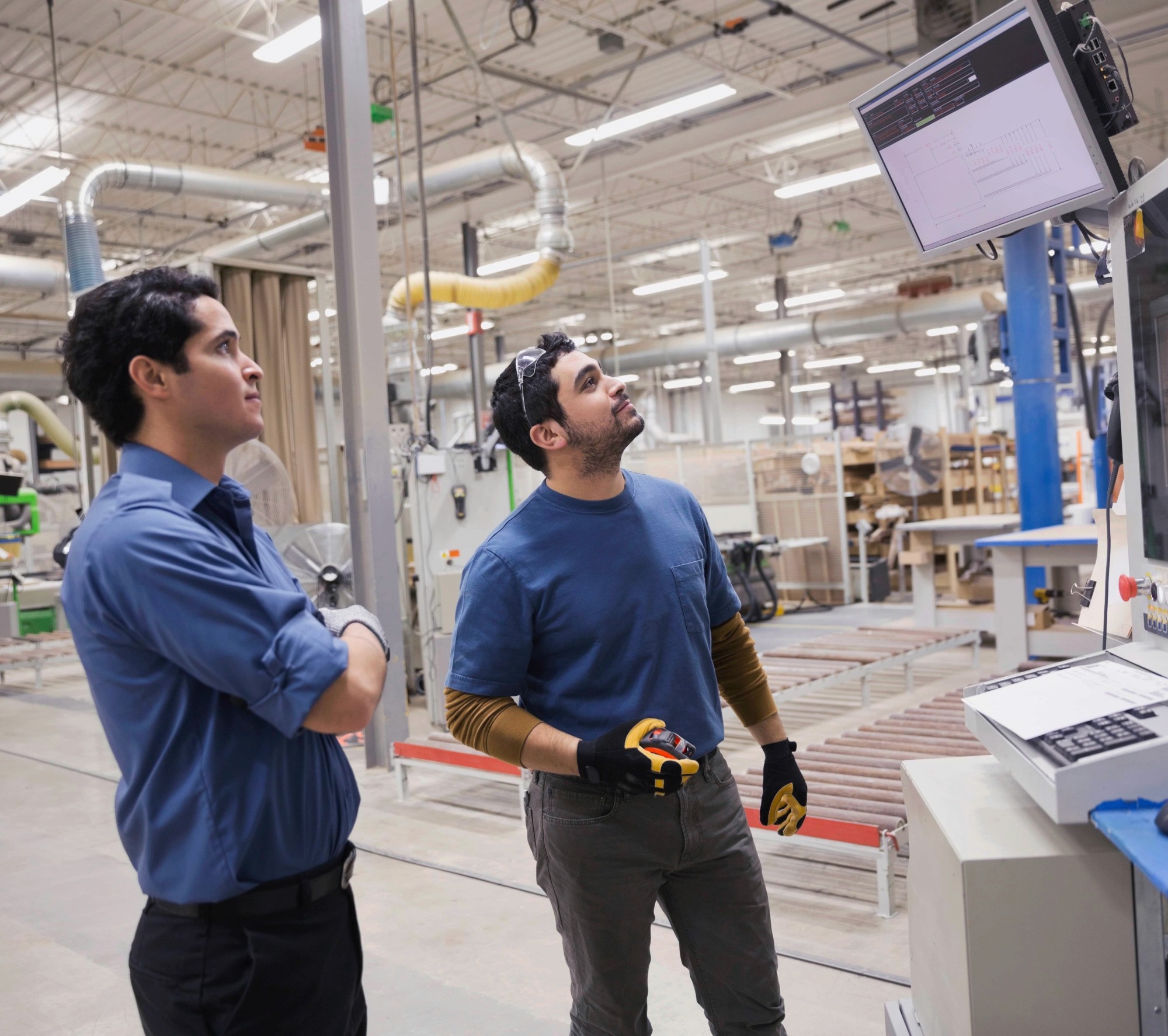 Deux hommes regardant un tableau de bord d'usine